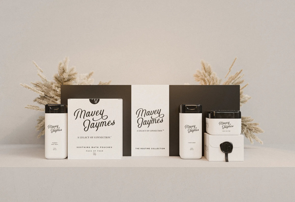 The Mavey Jaymes gift collection: Shampoo & Body Wash, Soothing Bath Pouches, The Routine Collection box, Conditioner and Body Butter on a shelf